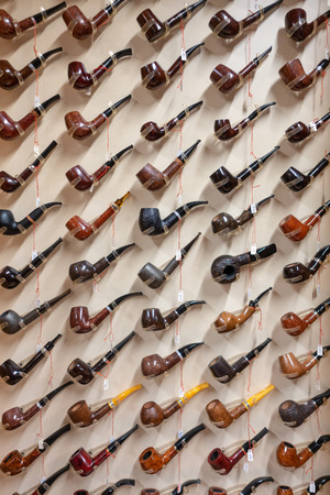 many tobacco pipes are hanging on a wall in a tobacco shopの写真素材