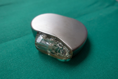 an explanted defibrillator on a green surgical drape