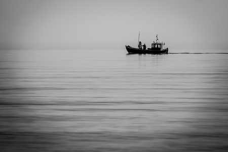 a fishing boat goes out to sea early in the morning when the sea is calmの写真素材