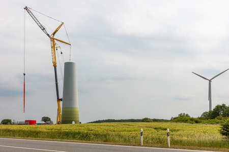 a new wind power plant is built on a field, half of the tower is already in placeの写真素材