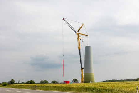 a new wind power plant is built on a field, half of the tower is already in placeの写真素材