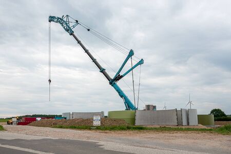 in the middle of a field, a wind turbine is erected with the help of a large craneの写真素材