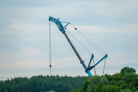in the middle of a field, a wind turbine is erected with the help of a large craneの写真素材