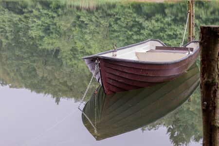 a chained rowing boat floats on a lakeの写真素材
