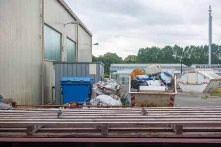 in a backyard there are garbage containers and a container with scrap metalの写真素材