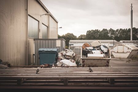 in a backyard there are garbage containers and a container with scrap metal
