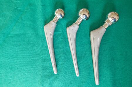 explanted hip prostheses lie spread out on a green surgical drapeの写真素材