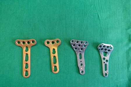 various explanted radius plates lie spread out on a green surgical drape