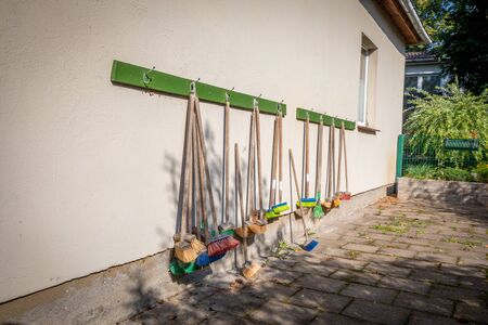 a lot of small coloured brooms hang on the outside wall of a kindergartenの写真素材