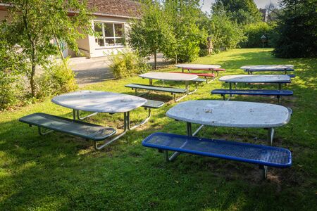 many small tables and benches stand on the lawn of a kindergartenの写真素材