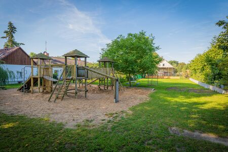 a wooden climbing frame stands on the premises of a kindergartenの写真素材
