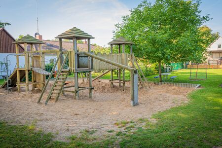 a wooden climbing frame stands on the premises of a kindergartenの写真素材