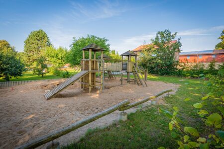 a wooden climbing frame stands on the premises of a kindergartenの写真素材