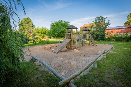 a wooden climbing frame stands on the premises of a kindergartenの写真素材