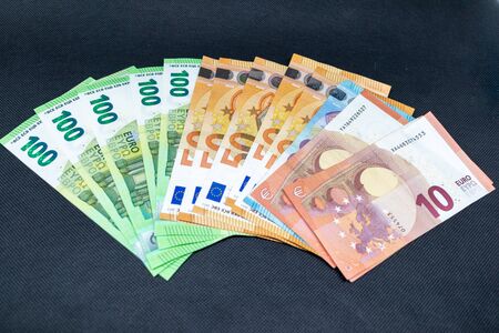 a lot of euro banknotes lying spread out on a dark table