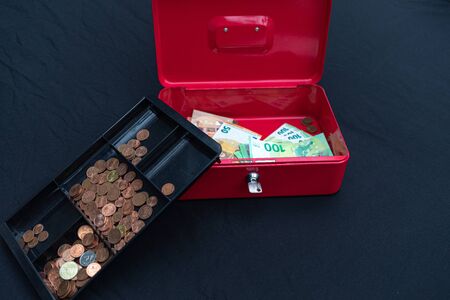 a lot of euro banknotes lie spread out in a red cash boxの写真素材