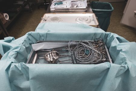 In a sterilization department in a hospital, cleaned instruments are wrapped in a blue cloth before the container is sterilized.の写真素材
