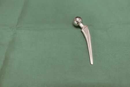 an explanted femoral prosthesis lies on a green surgical drapeの写真素材