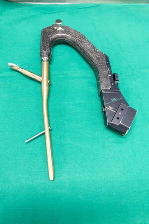 an explanted femoral nail with locking screw lies on a green surgical drapeの写真素材