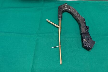 an explanted femoral nail with locking screw lies on a green surgical drapeの写真素材