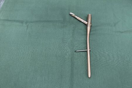 an explanted femoral nail with locking screw lies on a green surgical drapeの写真素材