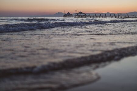 on a beach in the foreground are the waves and in the background is a golden sunsetの写真素材