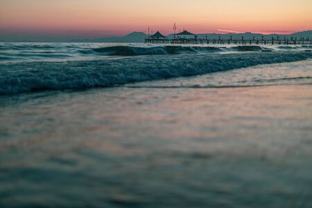 on a beach in the foreground are the waves and in the background is a golden sunsetの写真素材