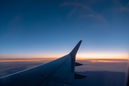the right wing of the plane rises into the blue skyの写真素材