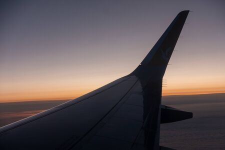 the right wing of the plane rises into the blue sky