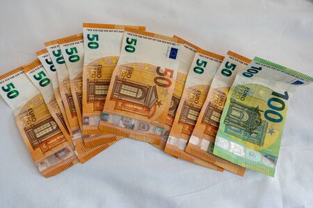 many euro banknotes are spread out on a bed with a white duvet coverの写真素材
