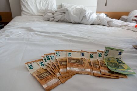 many euro banknotes are spread out on a bed with a white duvet coverの写真素材