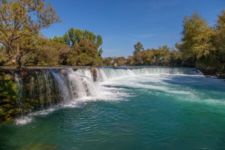 under a bright blue sky you can see the waterfall of Manavgatの写真素材