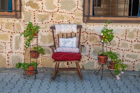 in an old street stands a decorative rocking chair and left and right are green plantsの写真素材
