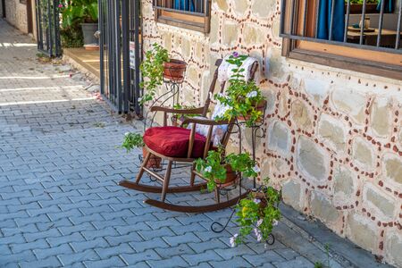 in an old street stands a decorative rocking chair and left and right are green plantsの写真素材