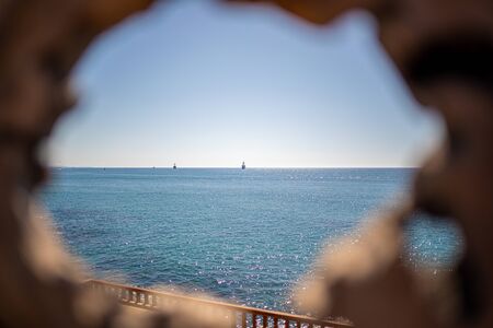 through a small hole in the wood you can see the blue seaの写真素材