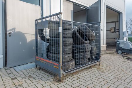 Many old tyres pile up in front of a garage to be disposedの写真素材
