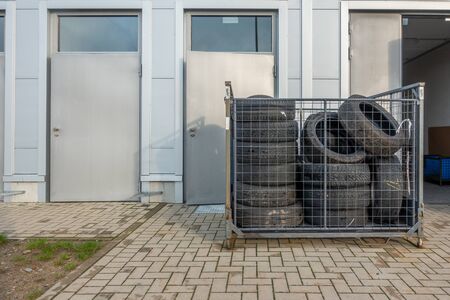 Many old tyres pile up in front of a garage to be disposedの写真素材