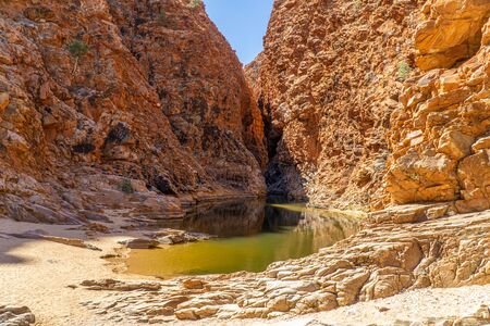 in the Australian outback there is a rugged rock formation with a waterholeの写真素材