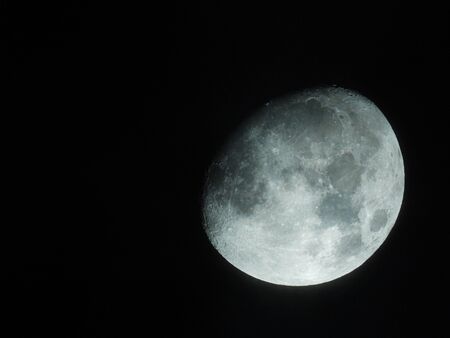 a bright three-quarter moon stands in the night skyの写真素材