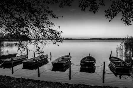 some rowboats lie at a lake in the north of Germany in the morning in autumnの写真素材