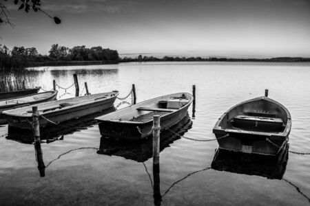 some rowboats lie at a lake in the north of Germany in the morning in autumnの写真素材