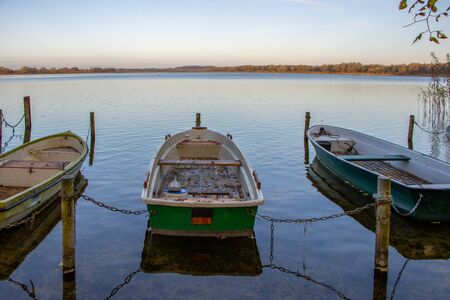 some rowboats lie at a lake in the north of Germany in the morning in autumnの写真素材