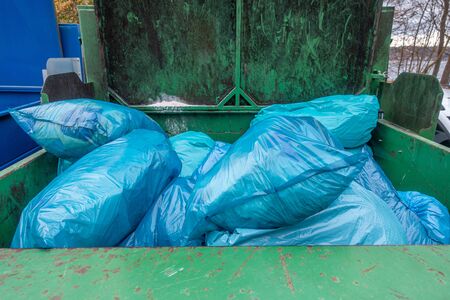 in a garbage compactor there are many blue garbage bags to be pressed togetherの写真素材