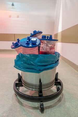 in a trash can in an operating theatre there are various suction containers filled with bloodの写真素材