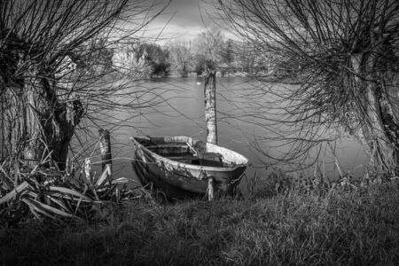 a lonely rowing boat lies on the shore of a lakeの写真素材