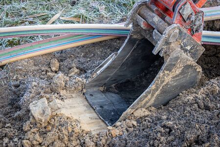 an excavator digging a trench to lay a high-speed Internet DSL cableの写真素材