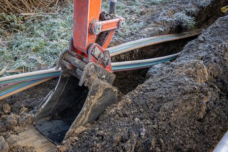 an excavator digging a trench to lay a high-speed Internet DSL cableの写真素材