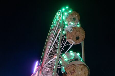 a giant Ferris wheel carousel shines in the night skyの写真素材