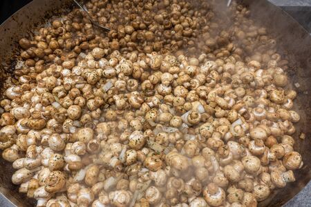 in a giant pan, delicious garlic mushrooms are preparedの写真素材