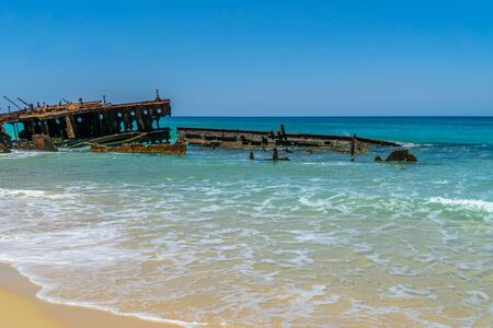 on the beach of fraser island lies the skeleton of a washed-up shipwreck in fine weatherの写真素材